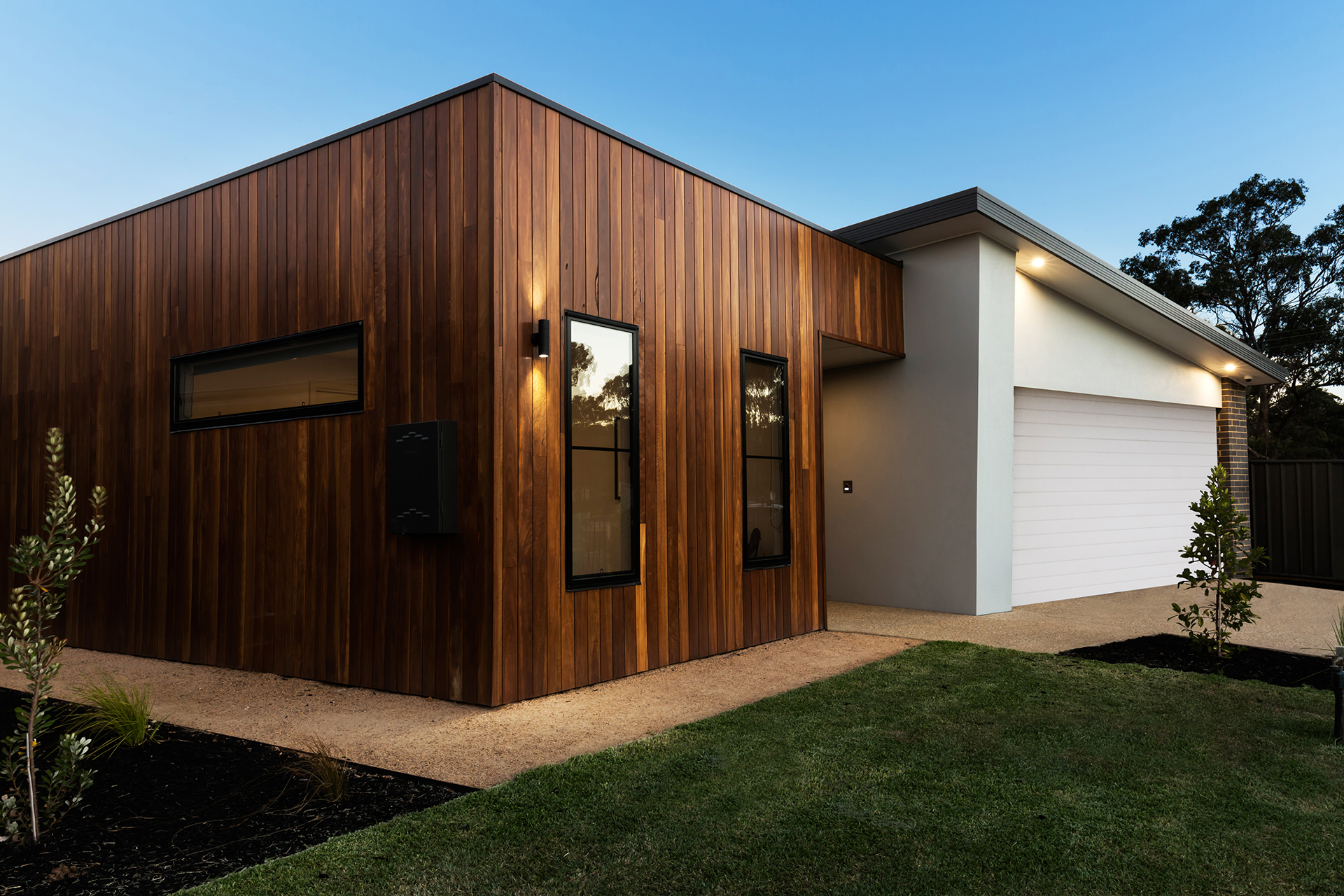 Angled view of white garage door installation with wood siding on home