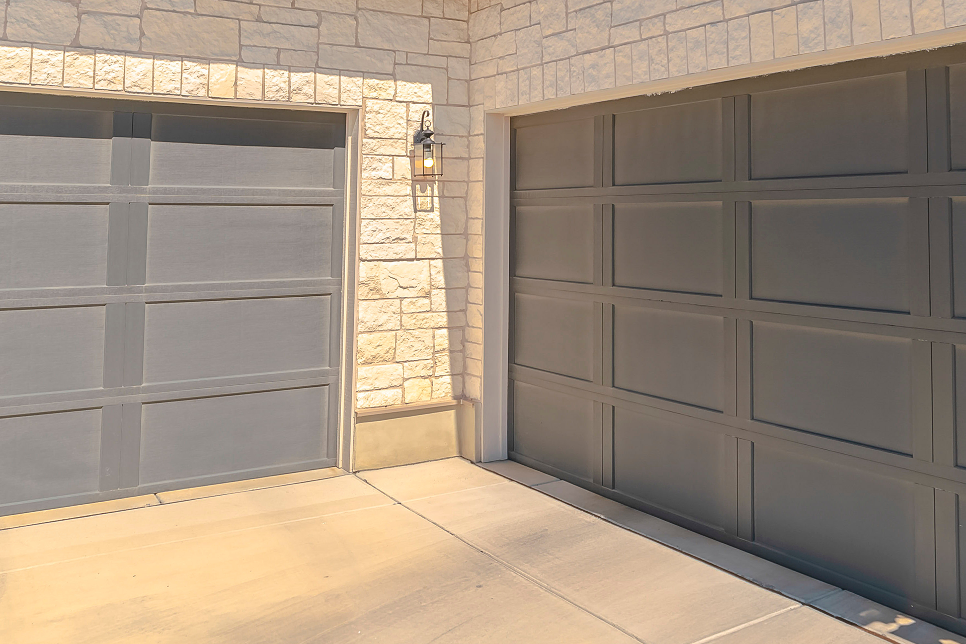 Gray steel garage door with panel design installed on stone façade in West Hills, CA